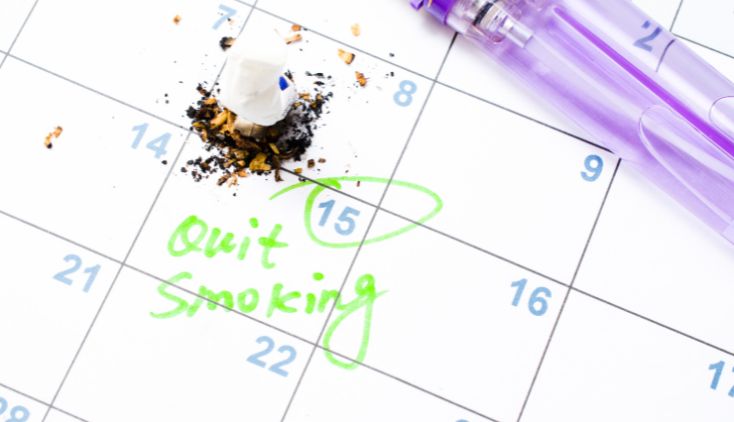 A calendar with a crushed cigarette on it. One of the days is highlighted with a note that says "quit smoking."
