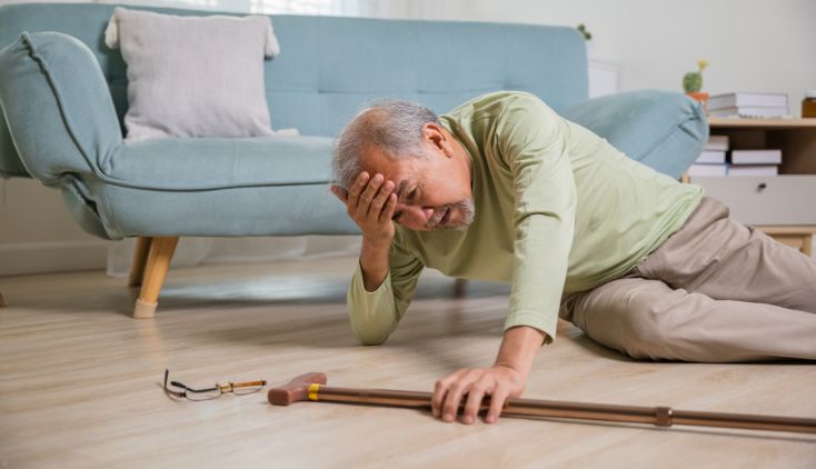 An older man who has fallen onto the ground. He has a cane in one hand.