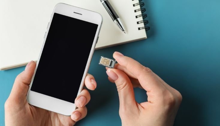 An image of hands inserting a new sim card into a cell phone.