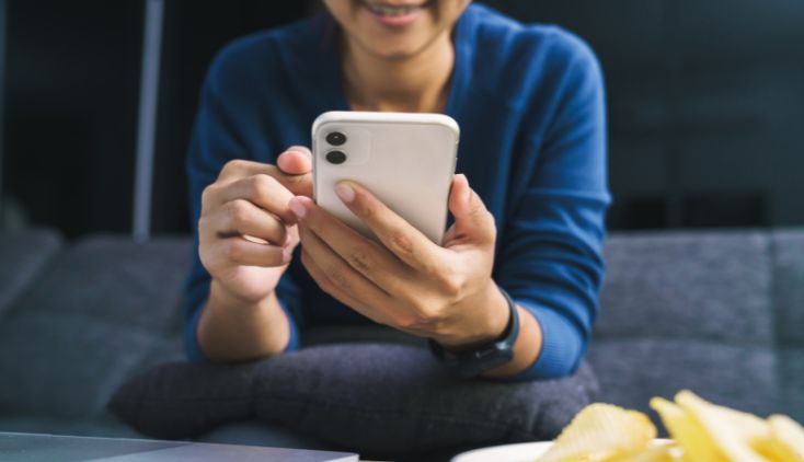 An older woman holding a white cell phone.