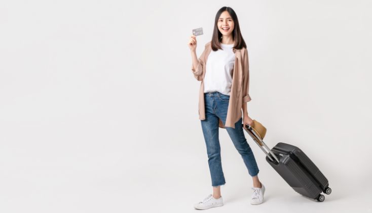 A woman with a black suitcase, holding a credit card.